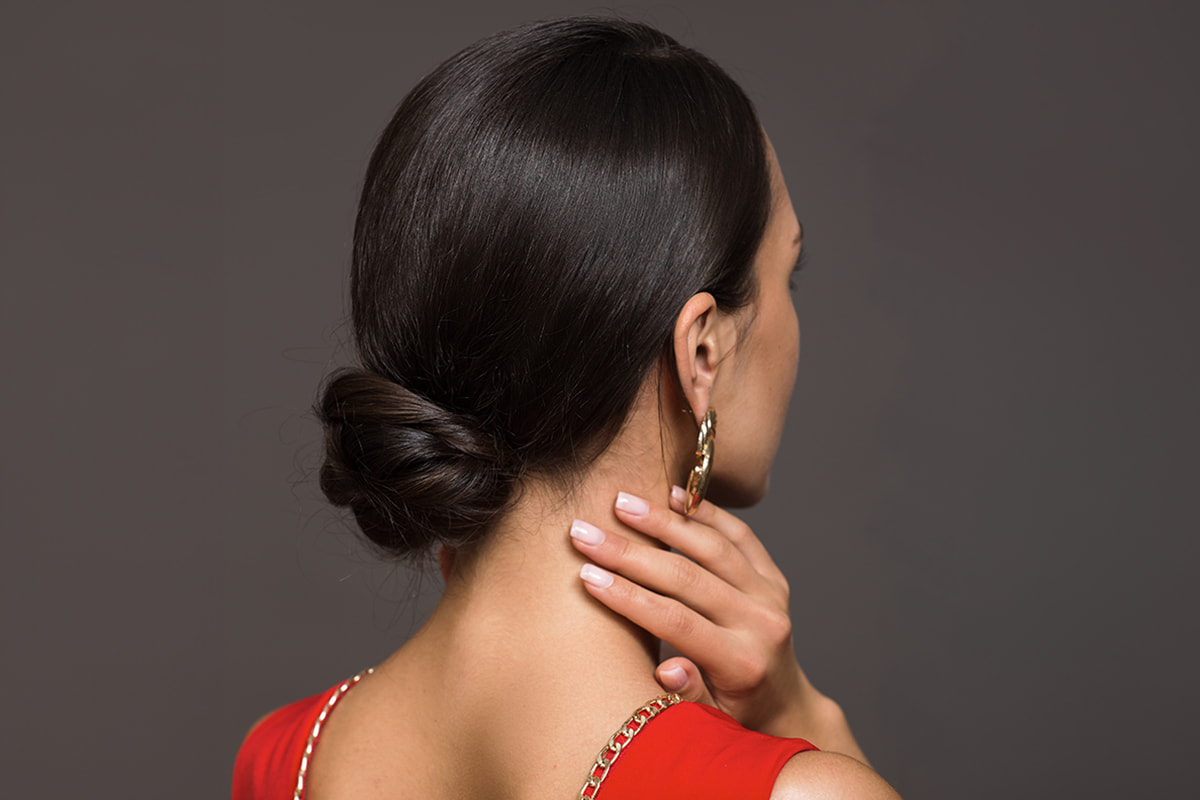 A woman wearing a red outfit facing away with slicked bun